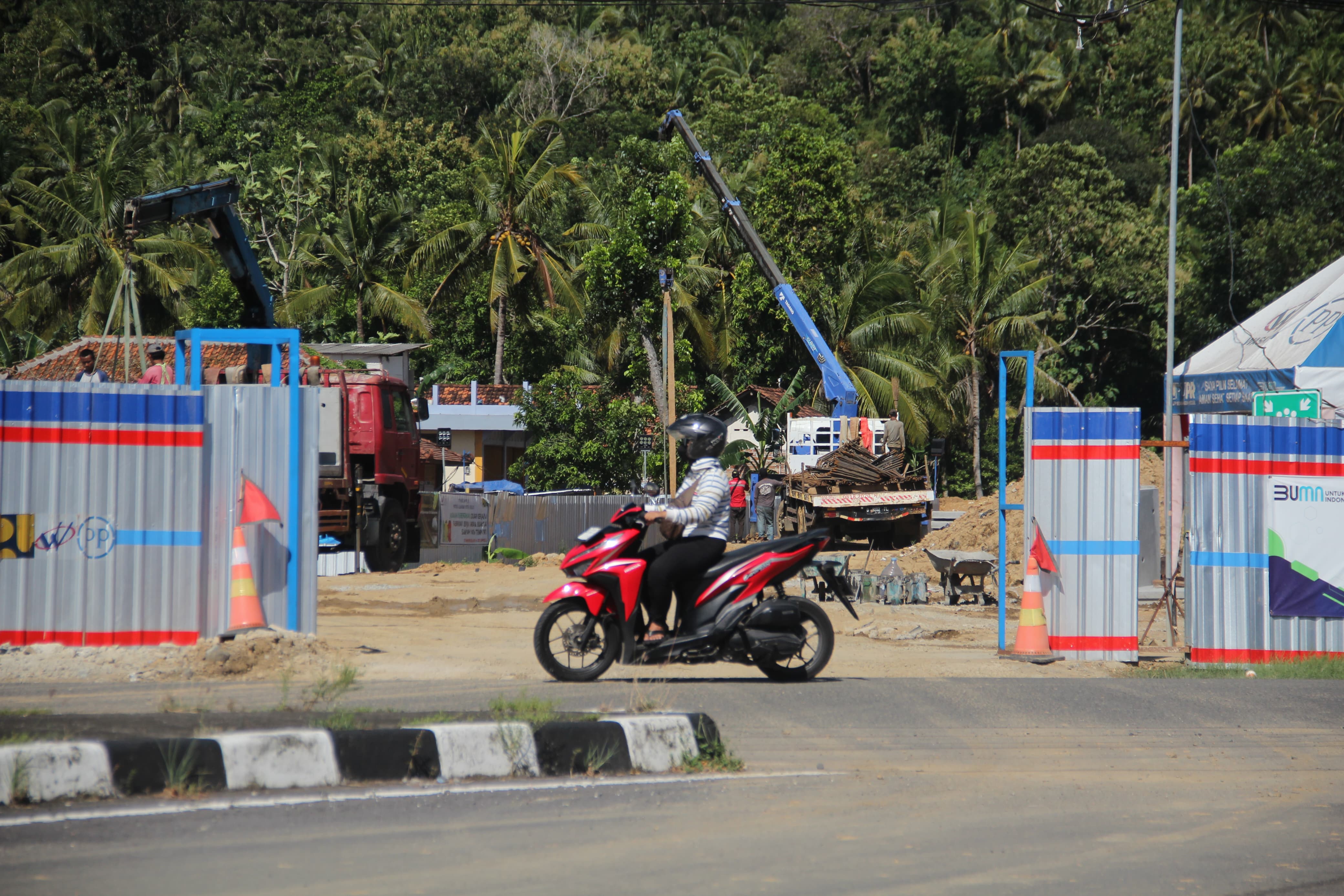 CEPAT: Pengendara melintas di depan proyek pengerjaan konstruksi Jalur Jalan Lintas Selatan (JJLS) Kelok 23 atau Jalan Baru Kretek-Girijati di Kalurahan Parangtritis, Kretek, Bantul, Rabu (20/3).