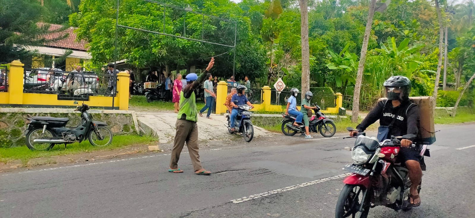 TOLERANSI: Mujiyono Nasuha menyeberangkan jamaah gereja yang hendak masuk ke kawasan gereja. (Anom Bagaskoro/Radar Jogja)