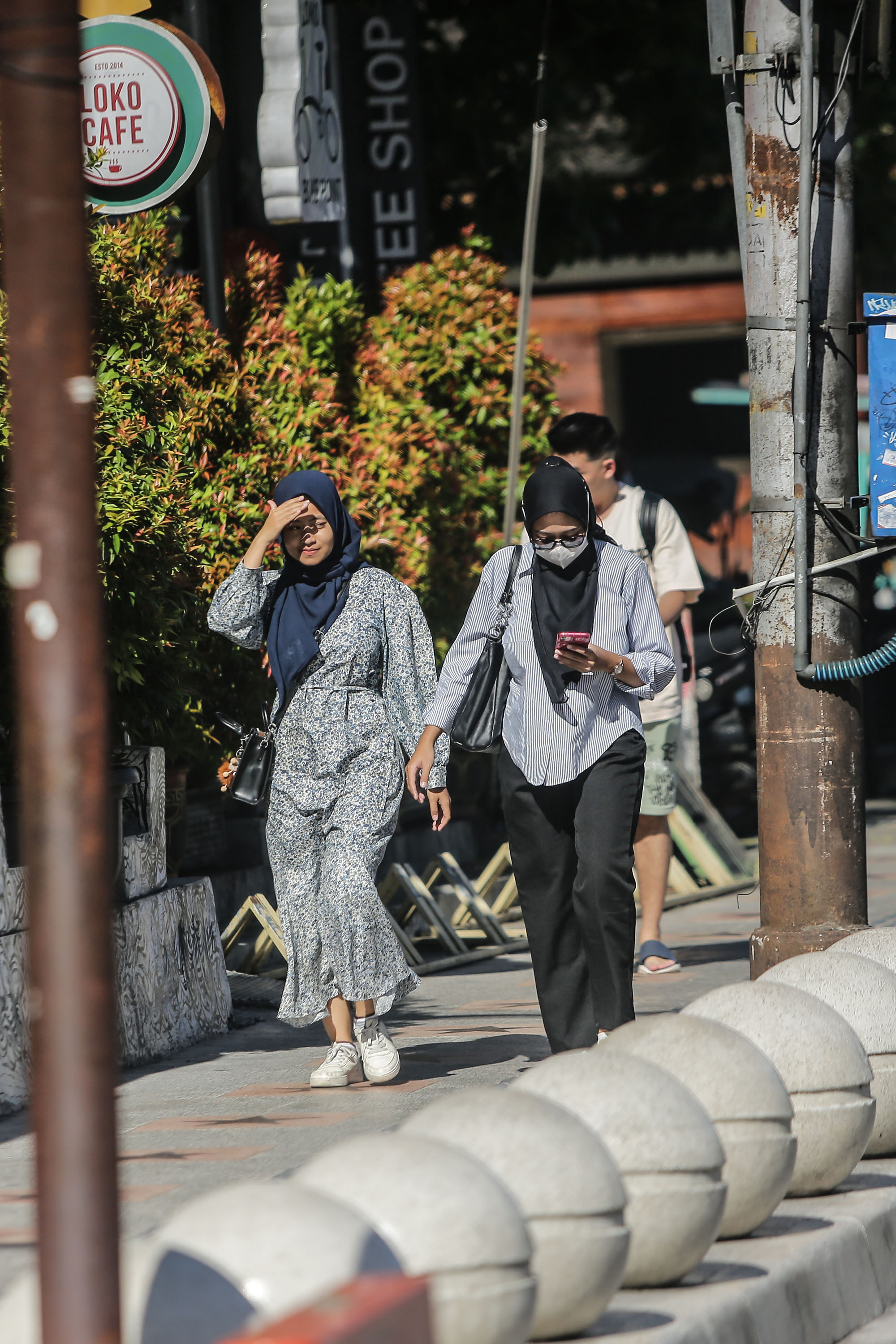 PANAS: Pengunjung berjalan menutupi wajah dari sengatan matahari saat berjalan di kawasan Malioboro, Jogja, Selasa (19/3).