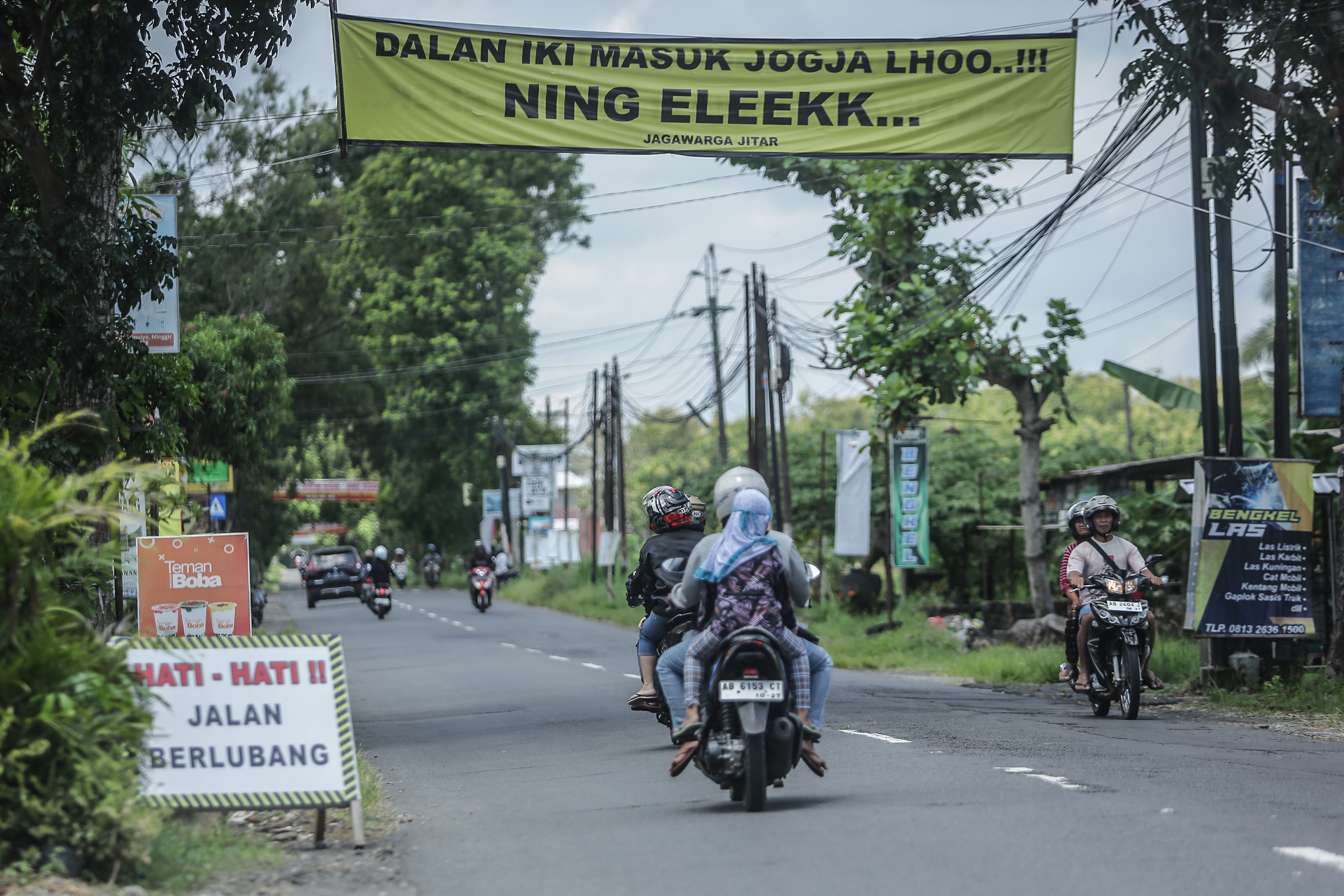HATI-HATI: Spanduk kritikan jalan rusak terpasang di jalan Sendangmulyo, Minggir, Sleman, Sabtu (30/3).
