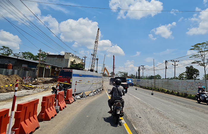 PROSES PENGERJAAN: Sejumlah kendaraan tampak melintas di Simpang Canguk. Sisi kanan-kiri jalan ditutup pagar besi.