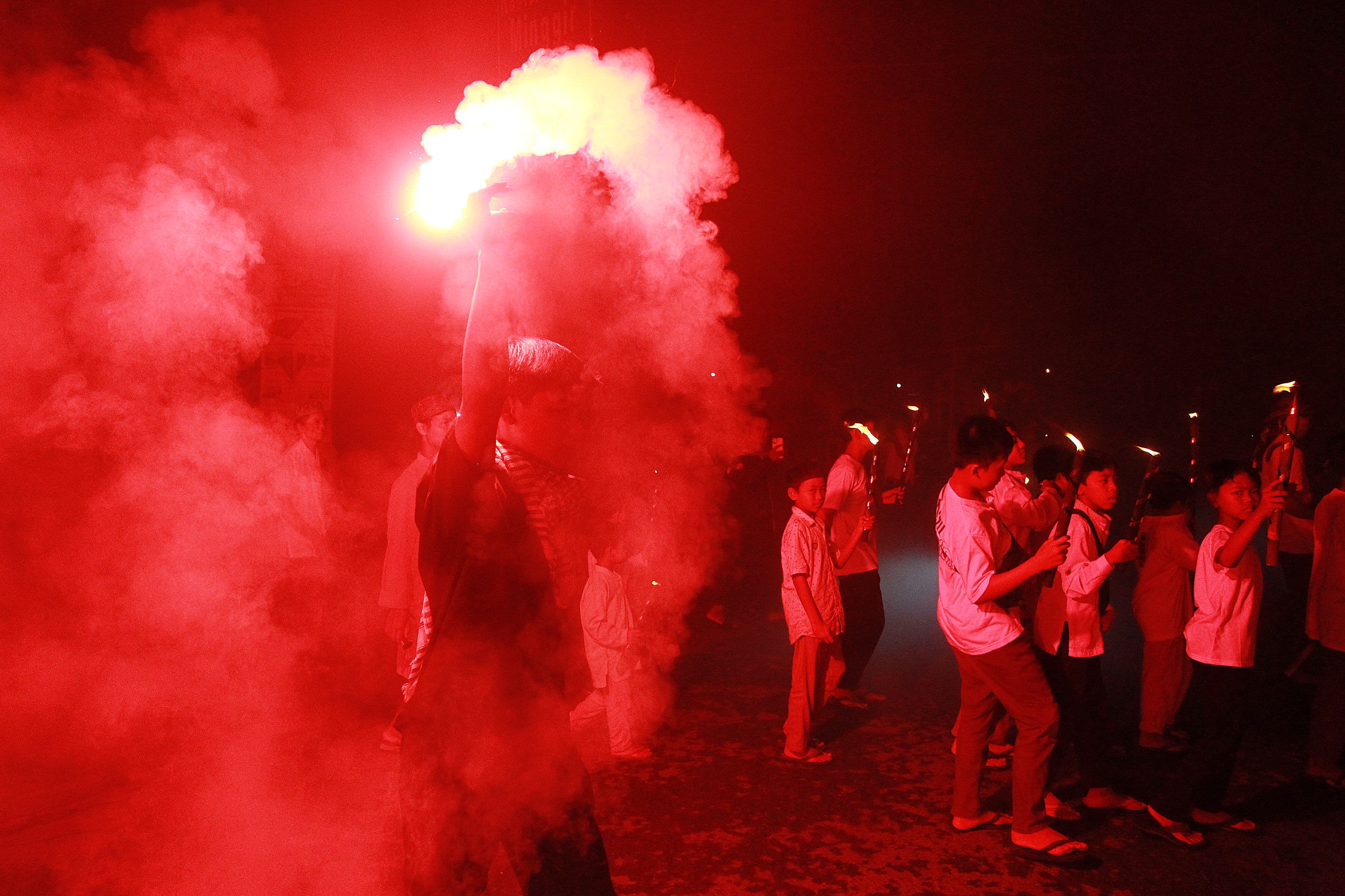 SEMARAK: Warga menyalakan flare dan membawa obor memeriahkan takbir keliling menyambut Idul Fitri 1445 H, di kawasan Ngaran, Margokaton, Seyegan, Sleman, Selasa malam (9/4).