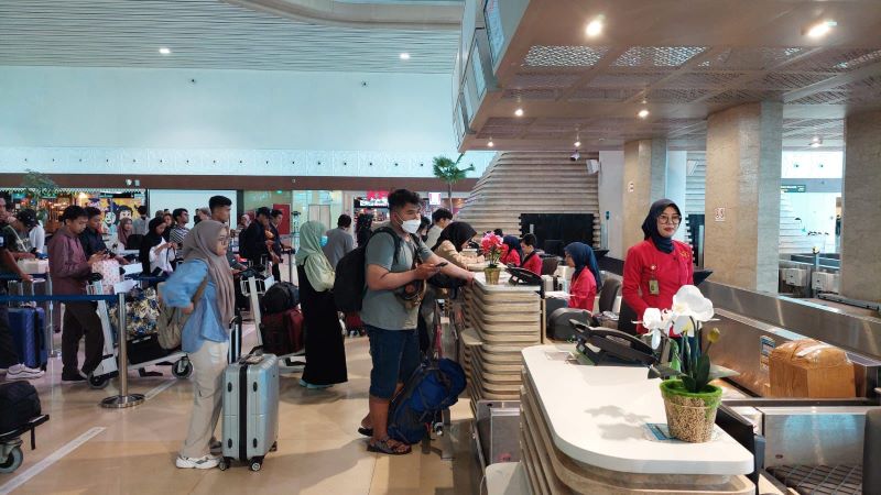 Penumpang mengantri di konter untuk memeriksa bagasi.