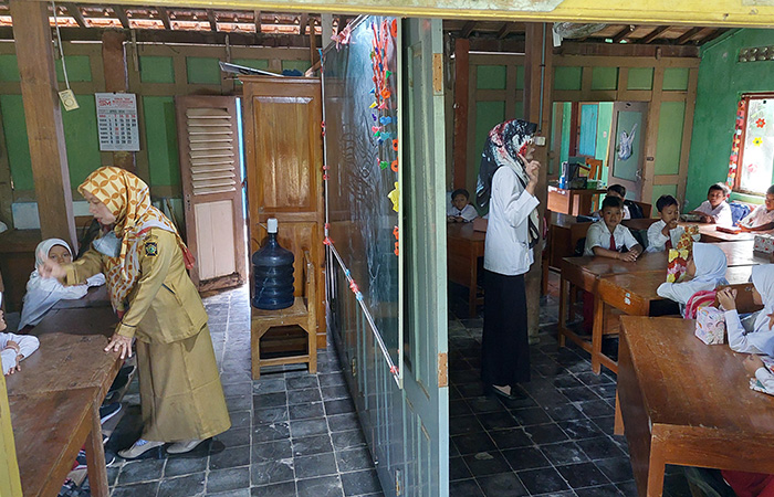 DARURAT: Siswa dua kelas berbeda di SDN Bugel sedang mengikuti kegiatan pembelajaran. Kelas mereka hanya dibatasi gebyok dari kayu.