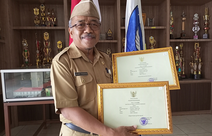 APRESIASI : Slamet Pramono, guru SMA Negeri 1 Kebumen memegang piagam penghargaan dari Bupati Kebumen Arif Sugiyanto atas dedikasinya menciptakan Himne dan Mars Kebumen.