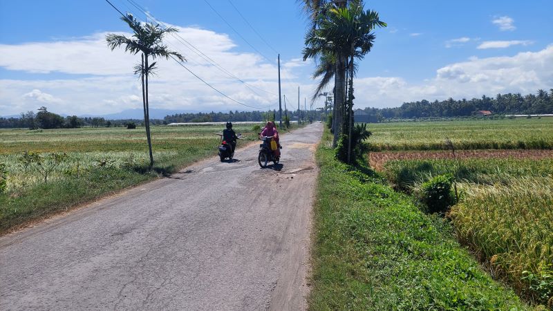 Rusak Parah: Tampak sepeda motor melabatkan kecepatannya karena jalan berlubang dan bergelombang.