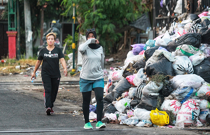 TERGANGGU: Warga menutup hidung saat melintas di dekat tumpukan sampah di depo Pengok, Demangan, Gondokusuman, Kota Jogja, (14/5).