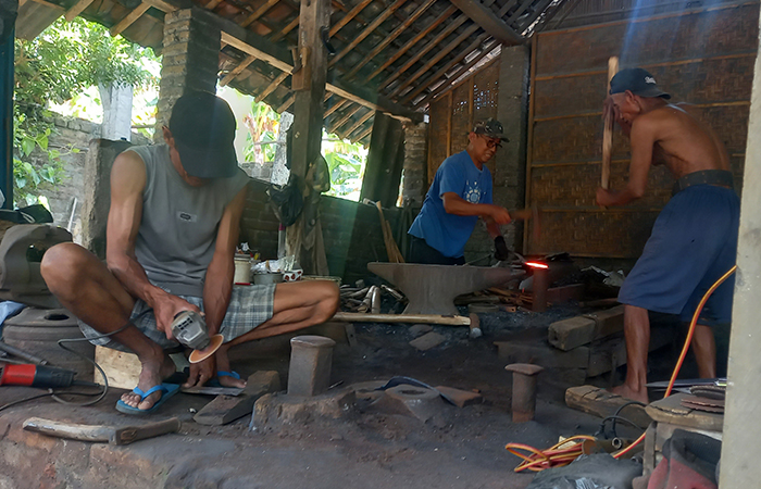 TRADISIONAL: Sarjono, salah seorang pandai besi di Dusun Karangasem, Gilangharjo, Pandak, Bantul dibantu sejumlah pekerjanya membuat pisau, sabit, dan lainnya menggunakan peralatan tradisional.