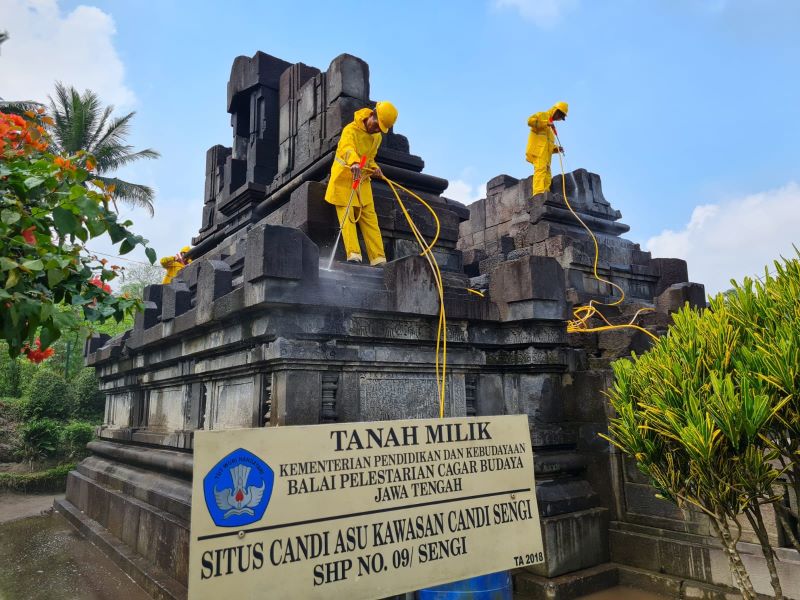 PEMBERSIHAN: Beberapa petugas tampak membersihkan bebatuan di Candi Asu sebagai upaya konservasi.&nbsp;