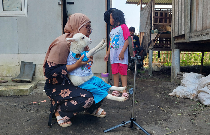 Irna memakaikan baju untuk Cemot. (Anom Bagaskoro)