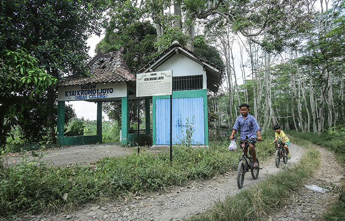 Anak-anak bersepeda melintas di samping makam Kiyai Kromo Ijoyo (Mbah Celeng) di kawasan Ketingan, Tirtoadi, Mlati, Sleman, Rabu (5/6).