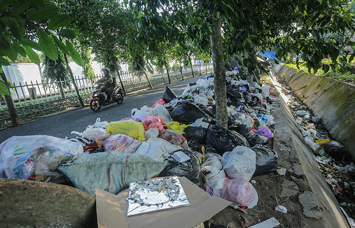 Pengendara motor melintasi tumpukan sampah liar di jalan Kusbini, Demangan, Jogja, Rabu (5/6).