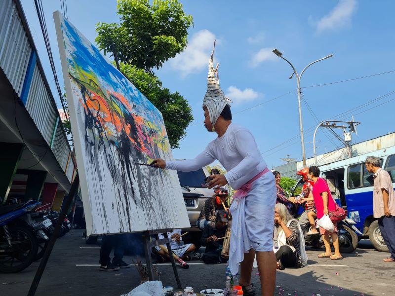 ARTISTIK: I Made Arya Dwita Dedok saat melukis on the spot di kawasan Pasar Rejowinangun, Senin (10/6/2024).