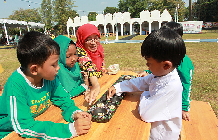 Anak-anak bermain permainan tradisional Dakon dalam Festival Jogja Tempo Doeloe bertema