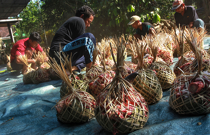 Warga mengemas daging kurban menggunakan kreneng atau keranjang bambu dan daun jati, di Ngaran, Margokaton, Seyegan, Sleman, Senin (17/6).&nbsp;