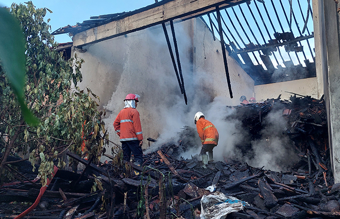 TERBAKAR: Tim Damkar memadamkan api pada tumpukan kayu.