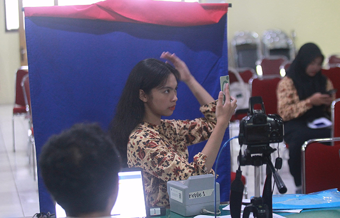 Seorang siswi berdandan sebelum melakukan perekaman Kartu Tanda Penduduk elektronik (KTP-el).