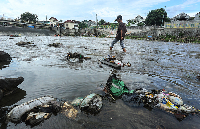 Warga mencari ikan diantara sampah yang hanyut di Kali Code kawasan Wirogunan, Mergangsan, Jogja, Kamis (4/7).