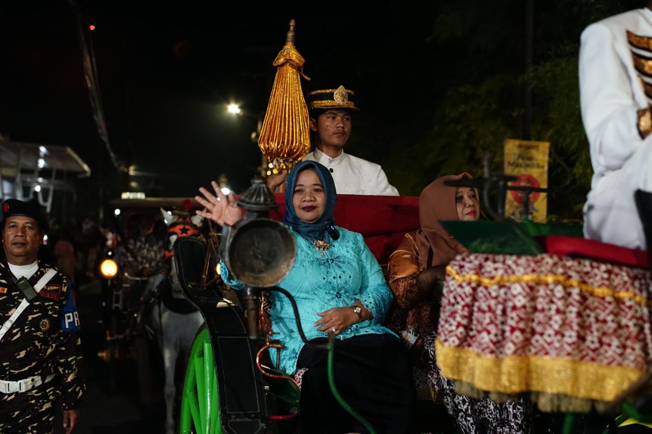 PARTISIPASI: Bupati Sleman Dra Hj. Kustini Sri Purnomo naik andong mengikuti kirab budaya Suran Mbah Demang di Kalurahan Banyuraden, Gamping, Sabtu (13/7/2024).