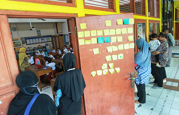 Orang tua memantau dari luar ruang kelas saat siswa baru mengikuti kegiatan Masa Pengenalan Lingkungan Sekolah (MPLS) pada hari pertama masuk sekolah di SD Negeri Percobaan 2, Depok, Sleman.