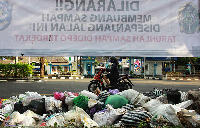 Pengguna jalan melintas di dekat tumpukan sampah liar di Jalan Wolter Monginsidi, Kota Jogja, (7/7).
