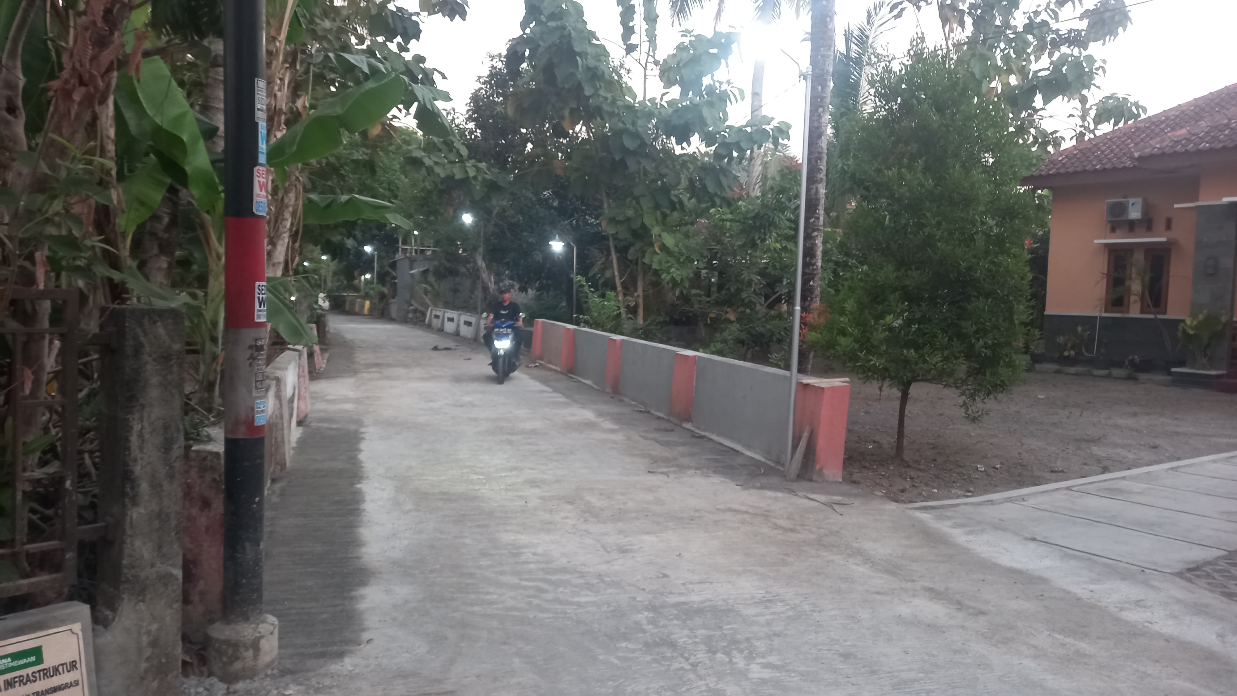 LEBIH NYAMAN: Dwi Mustofa mengendarai sepeda motor melintasi jalan yang selesai dicor.