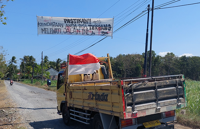 BENTUK PROTES: Baner bertuliskan penggambaran jalan rusak menghias ruas Jalan Cerme-Demangan Minggu(4/8).
