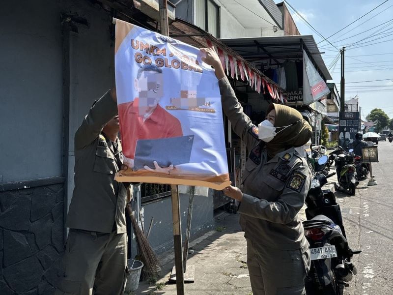 CAPTION: Petugas Satpol PP Kota Jogja saat melakukan penertiban reklame milik bakal calon wali kota yang terbukti melanggar pada Kamis (9/8/2024.
