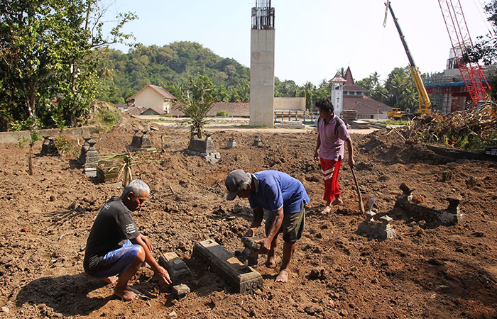 Warga menyelesaikan proses relokasi dan peninggian makam yang terdampak proyek Tol Jogja-Bawen, di pemakaman Druju Karang, Kalurahan Margodadi, Seyegan, Sleman, Selasa (13/8).