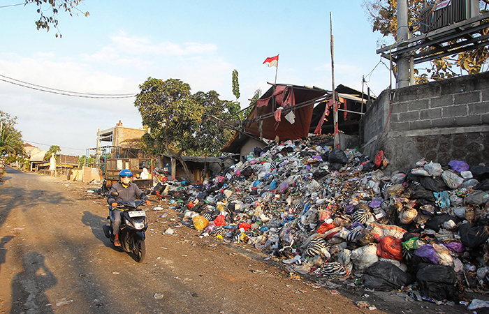 Pengguna jalan melintas di dekat tumpukan sampah di Jalan Wiyoro Baru, Baturetno, Bantul.