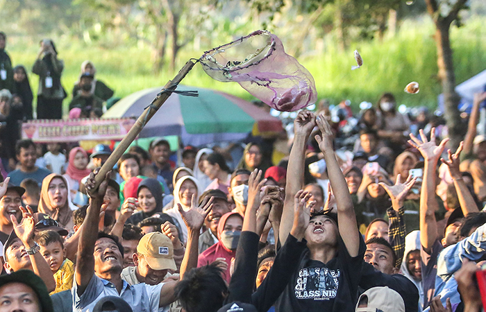 Warga berebut kue apem yang dibagikan dari atas menara saat saparan wonolelo, di kompleks makam Ki Ageng wonolelo, Wedomartani, Ngemplak, Sleman, Jumat (16/8).
