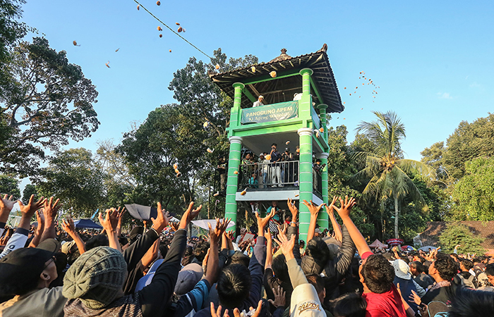 Warga berebut kue apem yang dibagikan dari atas menara saat saparan wonolelo, di kompleks makam Ki Ageng wonolelo, Wedomartani, Ngemplak, Sleman, Jumat (16/8).