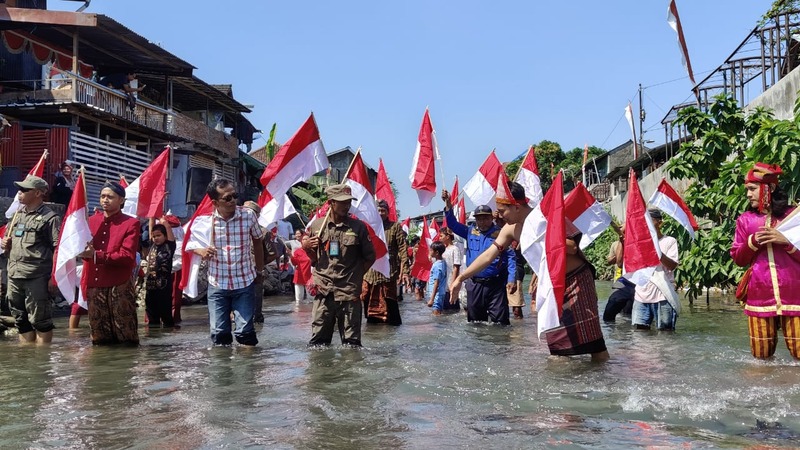 Puluhan Aliansi Mahasiswa dan Warga Kampung Ledok Tukangan saat mengibarkan bendera merah-putih untuk memeriahkan HUT RI yang ke-79 di Kali Code Sabtu (17/8/2024).