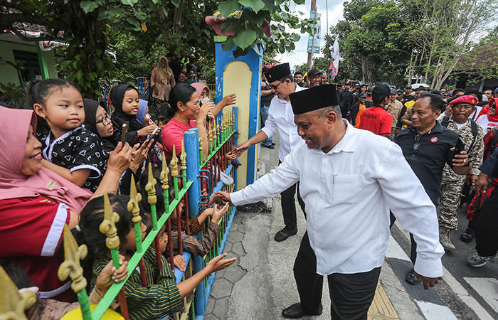 Pasangan calon bupati sleman Harda dan Danang menyapa warga saat arak-arakan menuju tempat pendaftaran di kantor KPU Sleman, Kamis (29/8).ELANG KHARISMA DEWANGGA/RADAR JOGJA