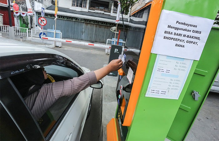 PERMUDAH PEMBAYARAN: Seorang pengendara mobil membayar retribusi parkir dengan aplikasi uang elektronik QRIS di TKP Ketandan, Jogja, kemarin. Pemda DIY resmi memberlakukan pembayaran nontunai.