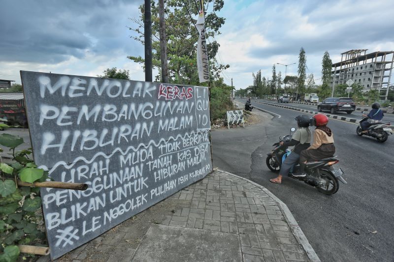 BENTUK PENOLAKAN: Kendaraan bermotor melintasi spanduk protes warga akan pendirian club malam di wilayah Kronggahan, Trihanggo, Gamping, Sleman Rabu (4/9/2024).