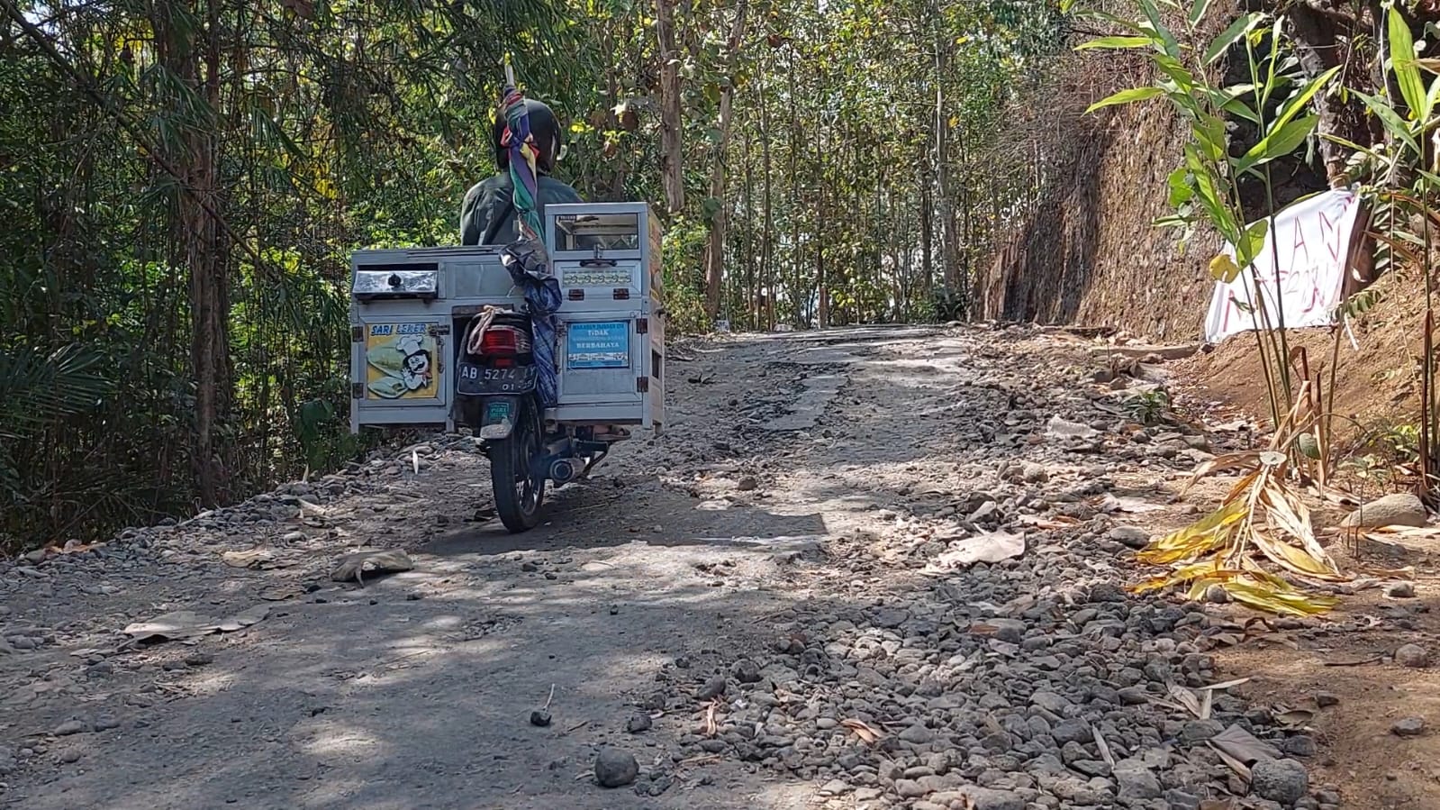 &nbsp;  SINDIRAN: Seorang pengendara motor melewati spanduk berisi sindiran terpasang di ruas Jalan Ngemplak-Krinjing Kidul, Kalurahan Kembang, Nanggulan, Kulon Progo.