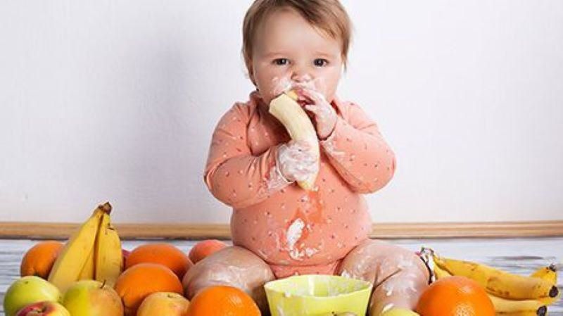 Ilustrasi anak makan buah pisang.