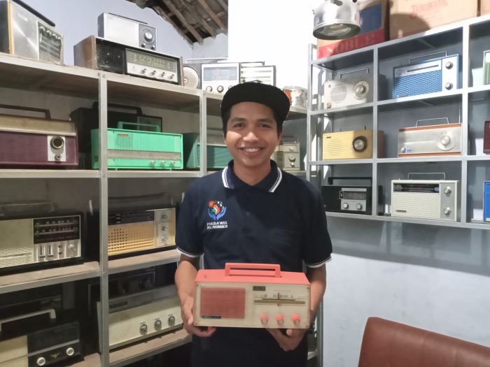 BARANG JADUL: Dimas Indra Febriyanto saat menunjukkan koleksi radio jadul yang memenuhi rak di ruang tamunya.