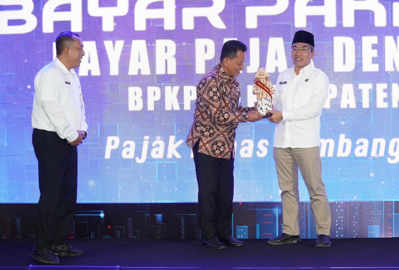 PERMUDAH LAYANAN: Abdul Halim Muslih (kanan) menyerahkan patung Pakde QRIS kepada Santoso Rohmad disaksikan Trisna Manurung. Itu sebagai simbol launching inovasi Bayar Pakde QRIS.