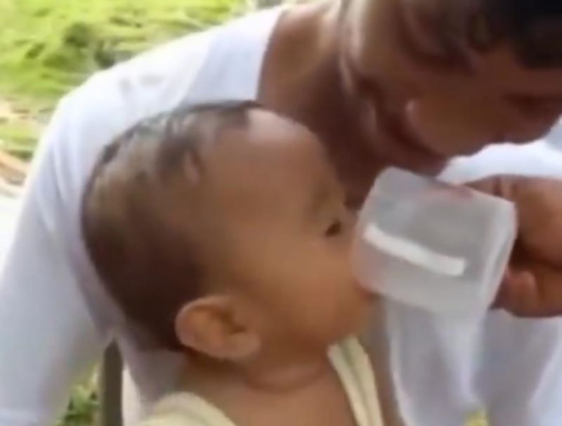 Yindakan bejat, pria dewasa memberikan minuman keras kepada bayi.