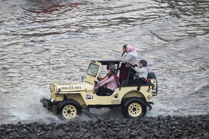 MEMACU ADRENALIN: Pengunjung saat mencoba menggunakan jip untuk melewati aliran sungai di lereng Gunung Merapi Senin (16/9/2024).