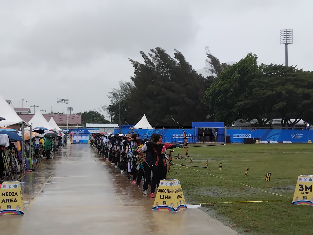SEMANGAT : Para atlet panahan PON 2024 bertanding di bawah guyuran hujan di Kompleks Stadion Harapan Bangsa (SHB), Selasa (17/9/2024).