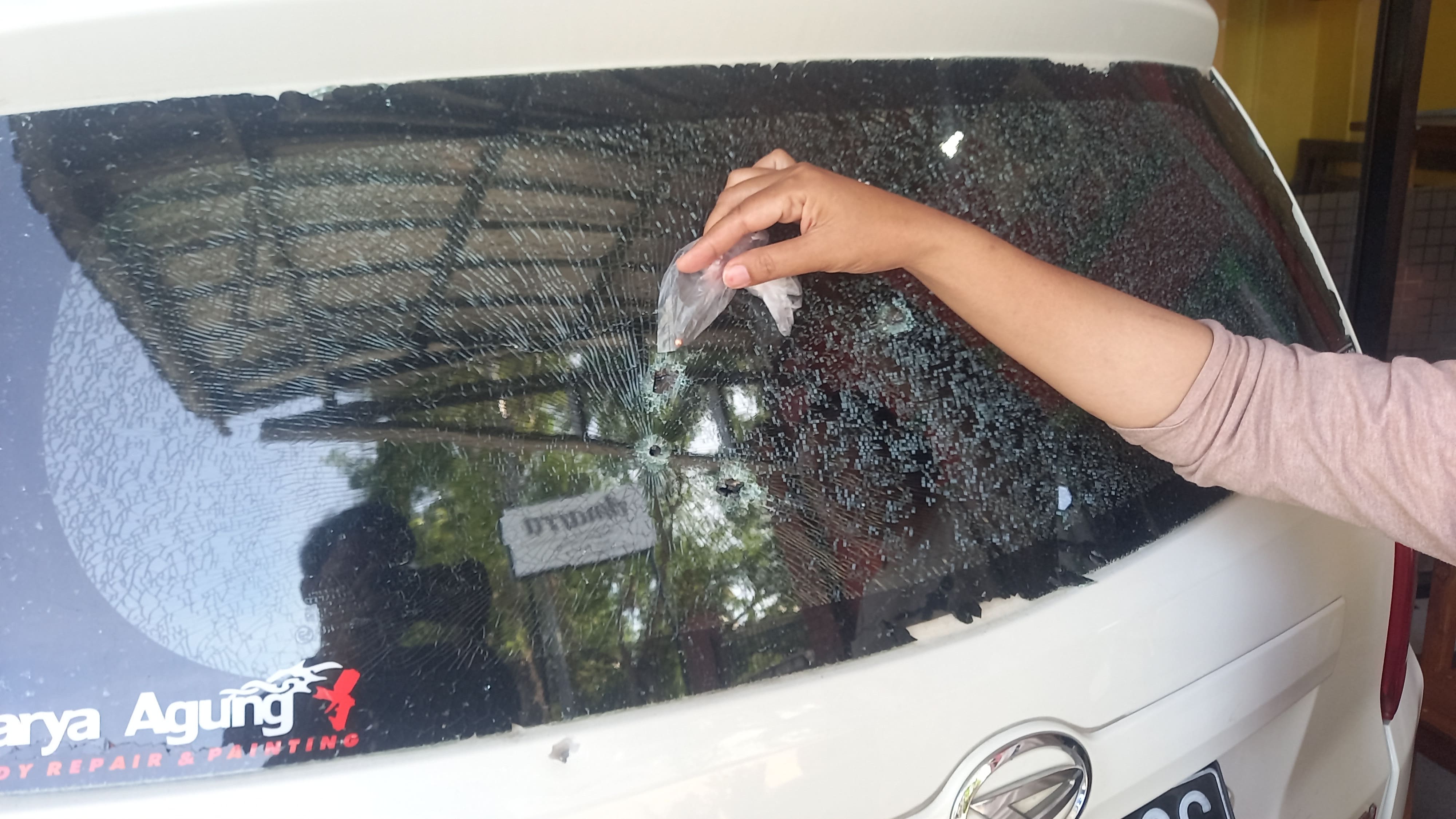 Kaca bolong mobil siti yang retak ditembakan airsoft gun beserta gotri yang ditemukan di sekitar rumah Siti.