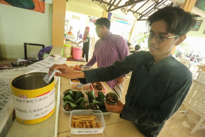 Siswa meletakan uang kedalam tempat pembayaran setelah memilih jajanan yang disajikan di kantin kejujuran sekolah SMAN 1 Bantul, Jumat (20/9/2024).