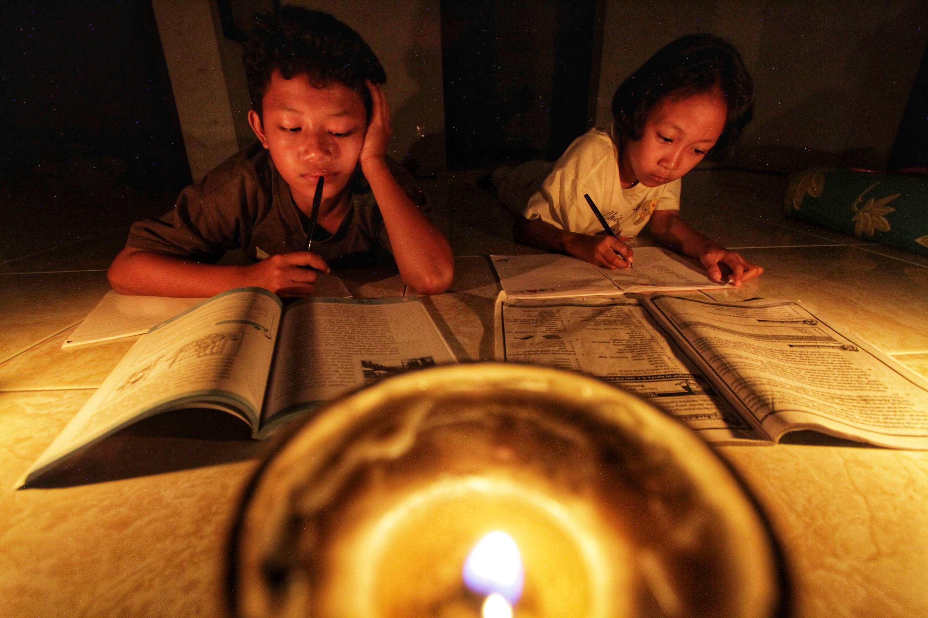 Dafa dan Icha belajar diterangi cahaya lilin saat listrik padam di Kampung Sorogenen, Ambarketawang, Gamping, Sleman, Selasa (3/9). Listik padam yang terjadi di sebagian besar wilayah DIJ dan Jateng sejak sore hari tersebut diakibatkan oleh kerusakan traf