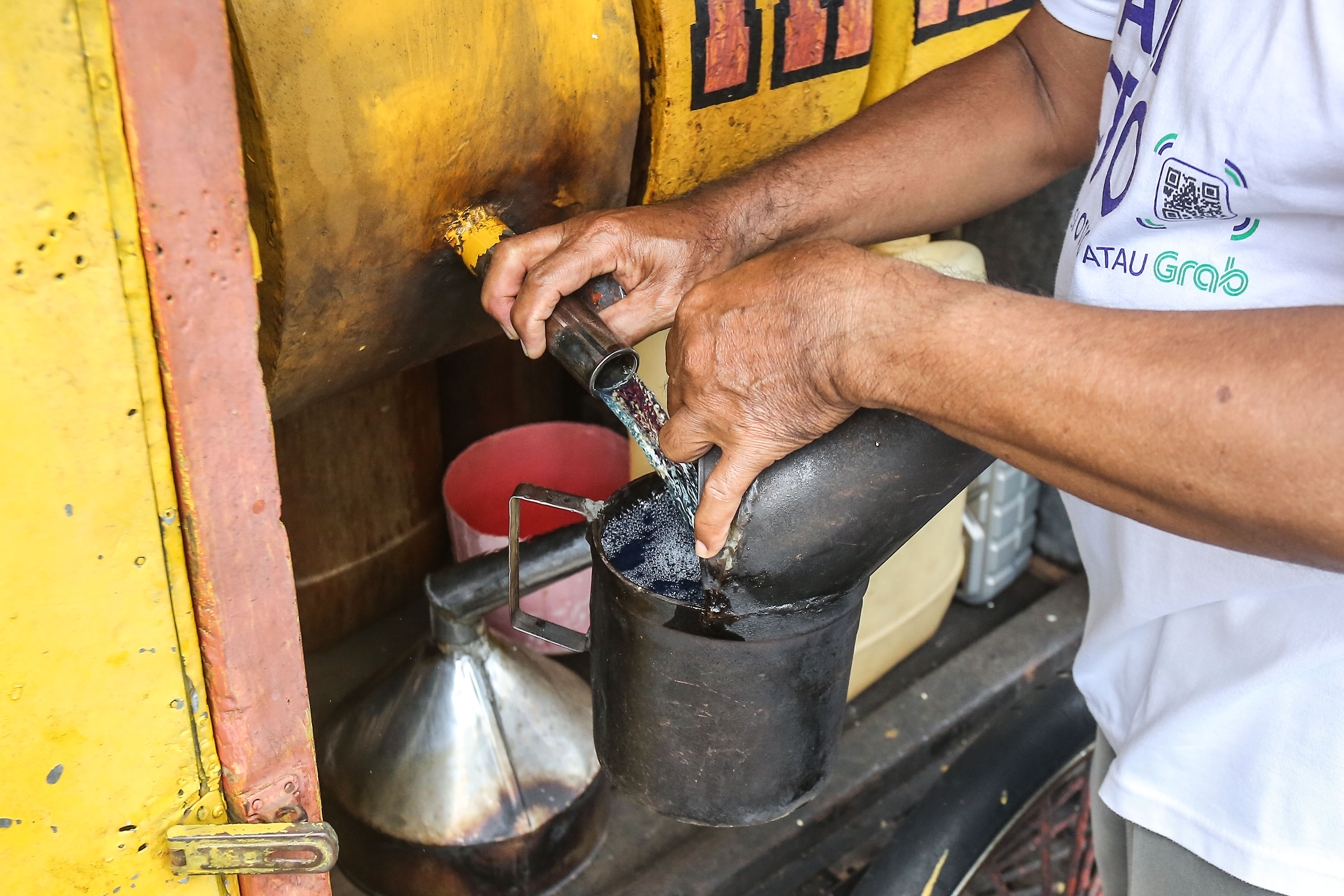 Penjual bensin eceran melayani pembeli dengan alat takar di kiosnya kawasan Kota Baru, Jogja, Sabtu (5/10). Penjual bensin dengan alat takar mulai jarang dijumpai saat ini (Foto: Elang Kharisma Dewangga).