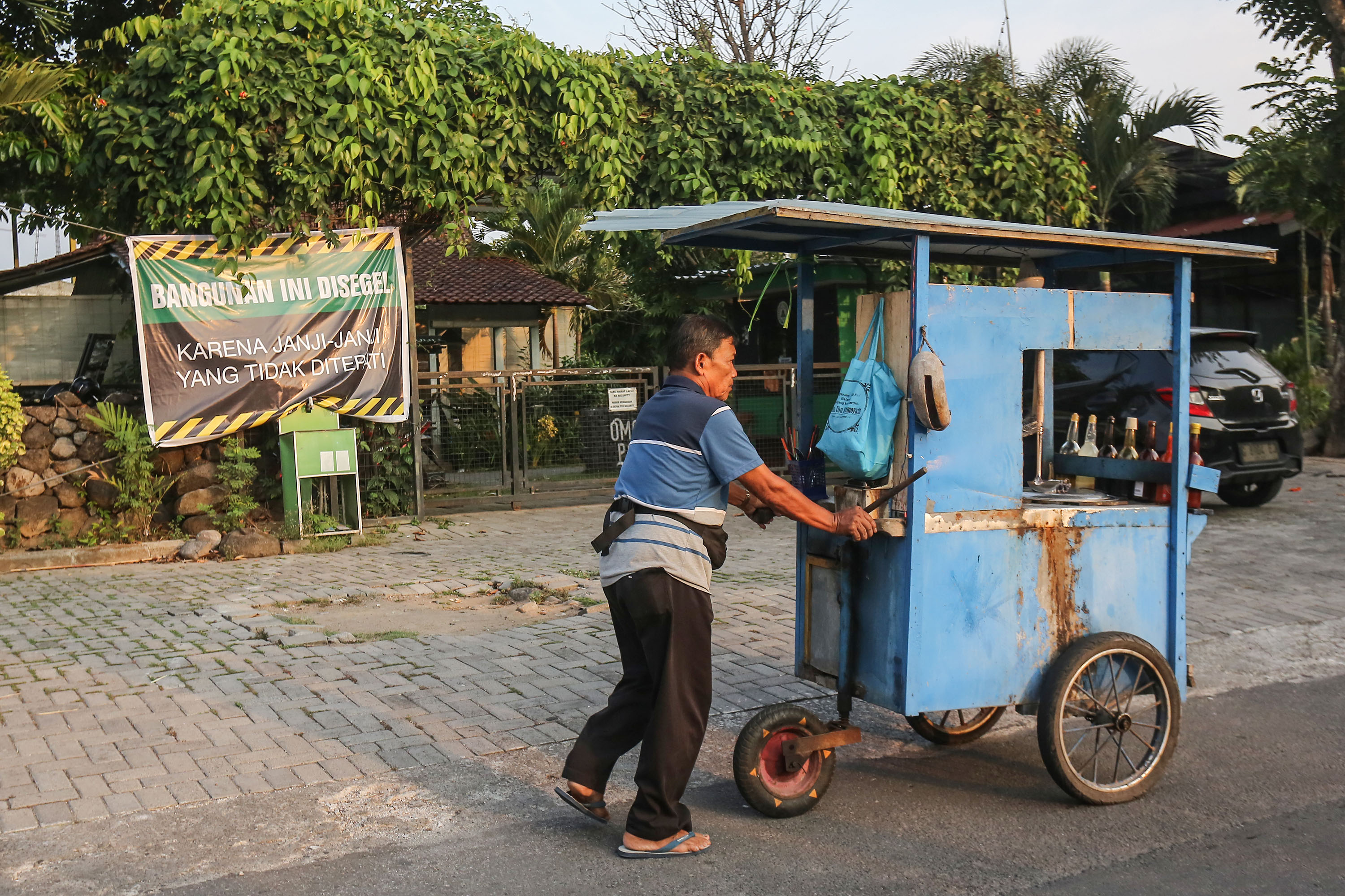 Pedagang mie ayam melintasi spaduk penyegelan di Omah PSS, Sariharjo, Ngaglik, Sleman, Sabtu (5/10). Penyegelan dilakukan BCS, suporter PSS karena manajemen yang tidak menepati janjinya.