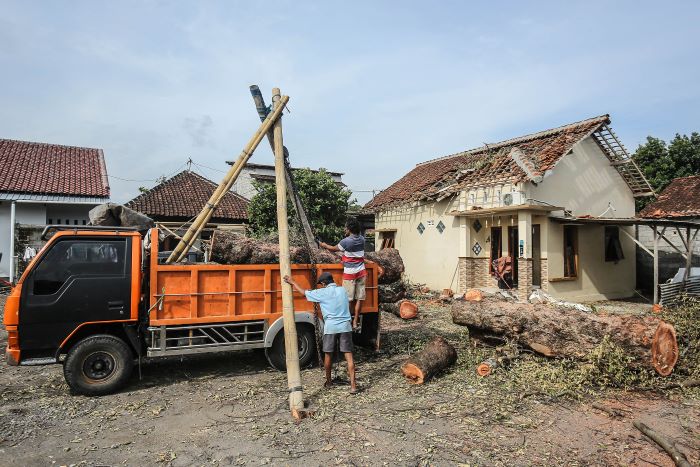 TERDAMPAK: Zanah pemilik rumah kontrakan membersihkan puing akibat tertimpa pohon bayur saat hujan disertai angin Senin lalu di kawasan Plosokuning, Minomartani