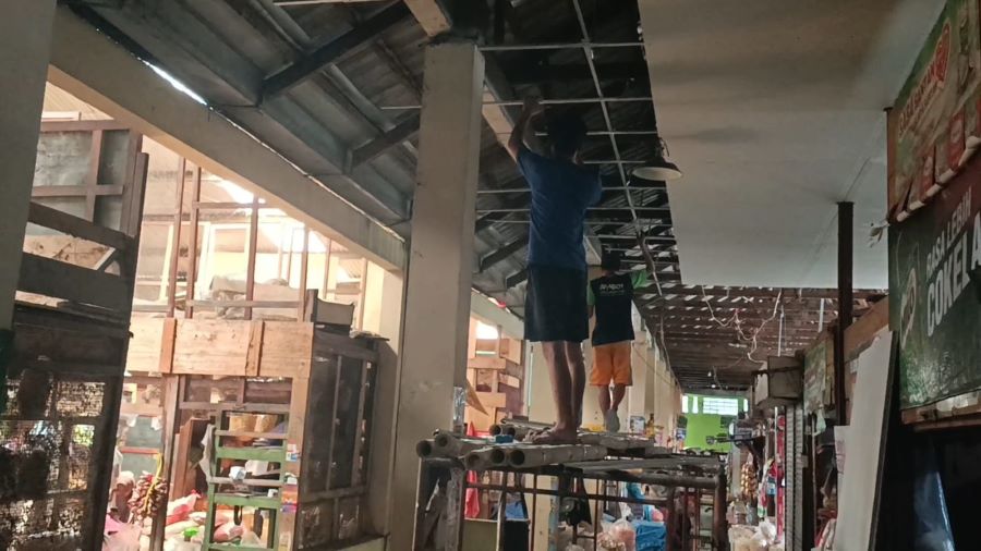 PERBAIKAN: Tukang memperbaiki bagian atap dan finishing pada tembok area penjualan daging.
